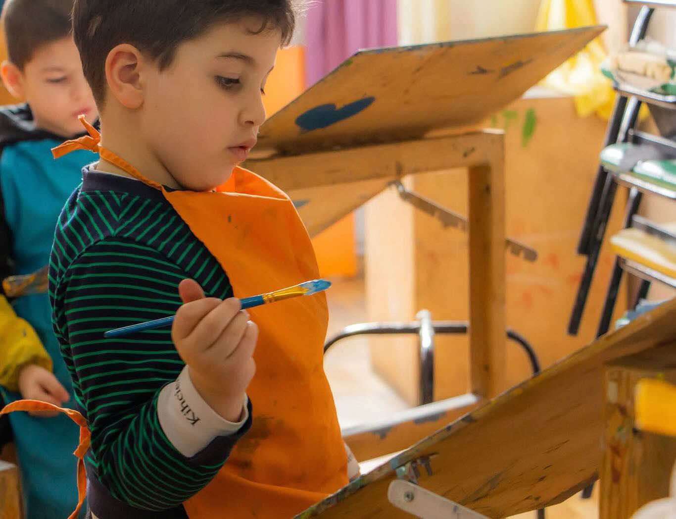 Child in orange apron painting