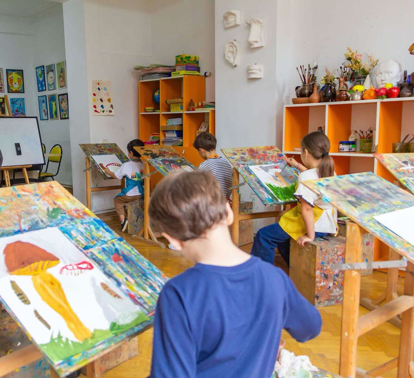 Children painting at easels from different angle